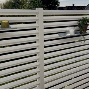 Hyllor på ett högre vitt staket på altanen.