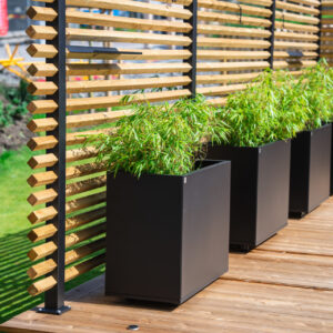 Drömminge staketstolpe med vriden 2-tums regel (45x45 mm), med Plant Boxar med planterad bambu i kruka. En svenskproducerad, underhållsfri lösning för avskärmning och vindskydd – vintergrönt och stilrent.