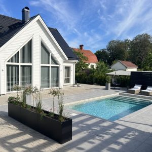 Ett långt planteringskärl vid en pool. Plant Box Flex från Wernamo Design. 