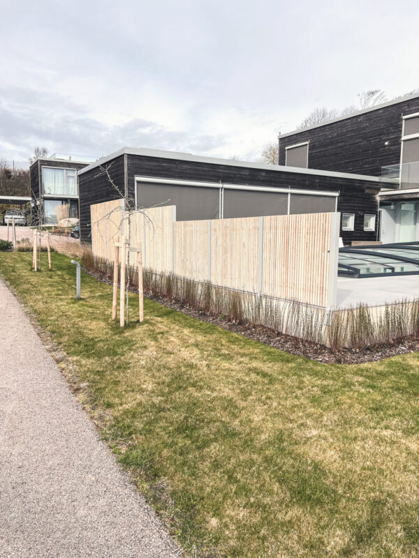 Avskärmning vid uteplats med pool. Ribbstaket med bra insynsskydd. Vindskydd i modern tappning. Silvergrå kulör och siiox behandlad träribba.