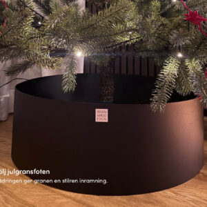 Svart trädring som döljer julgransfoten inomhus